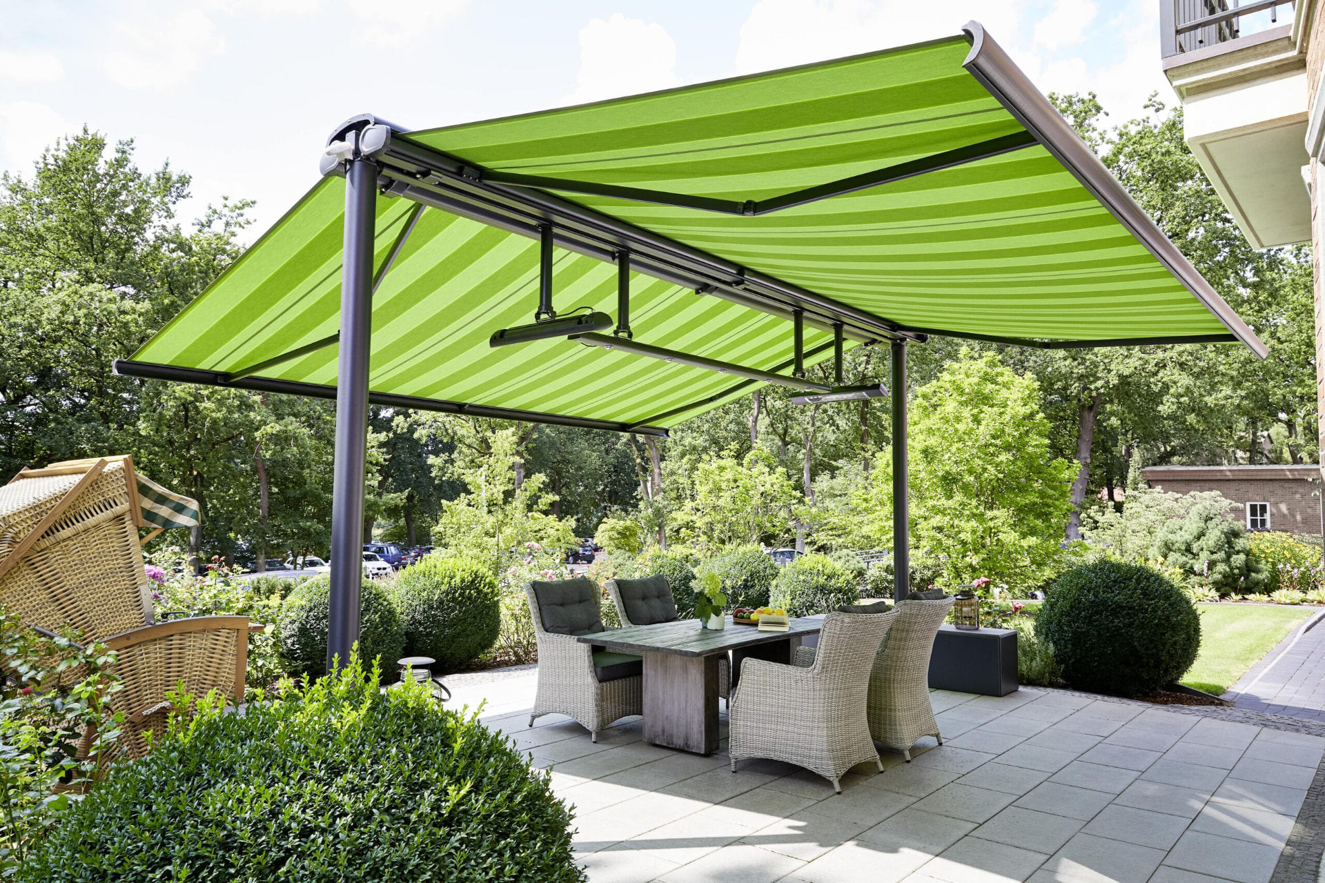 Markilux Syncra med grøn stribemarkisedug, antracitfarvede søjler og varmetstråler på en terrasse