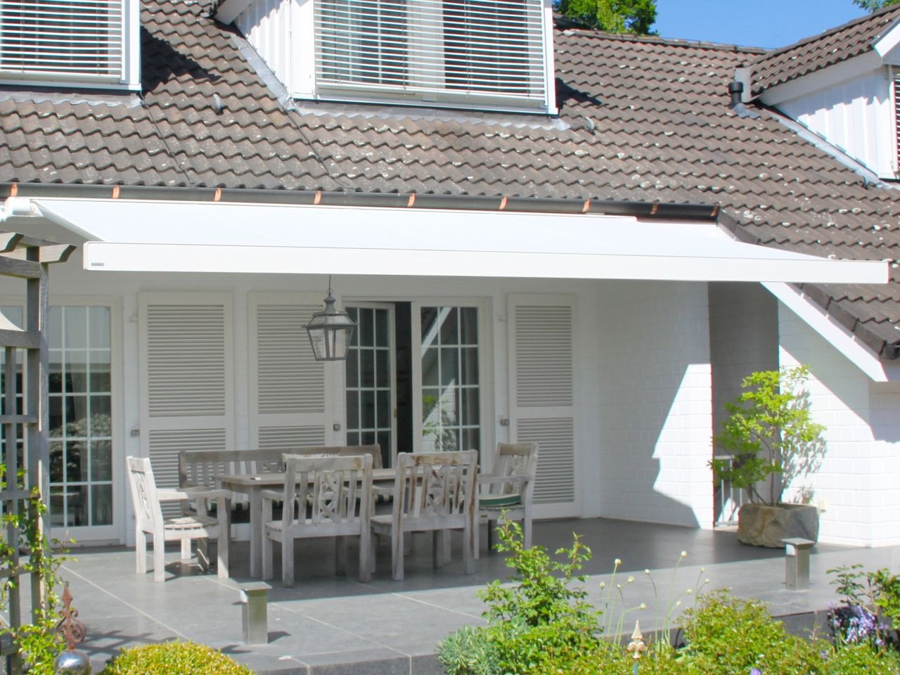 Hvid Markilux 970 kassettemarkise på terrassen ved en hvid villa