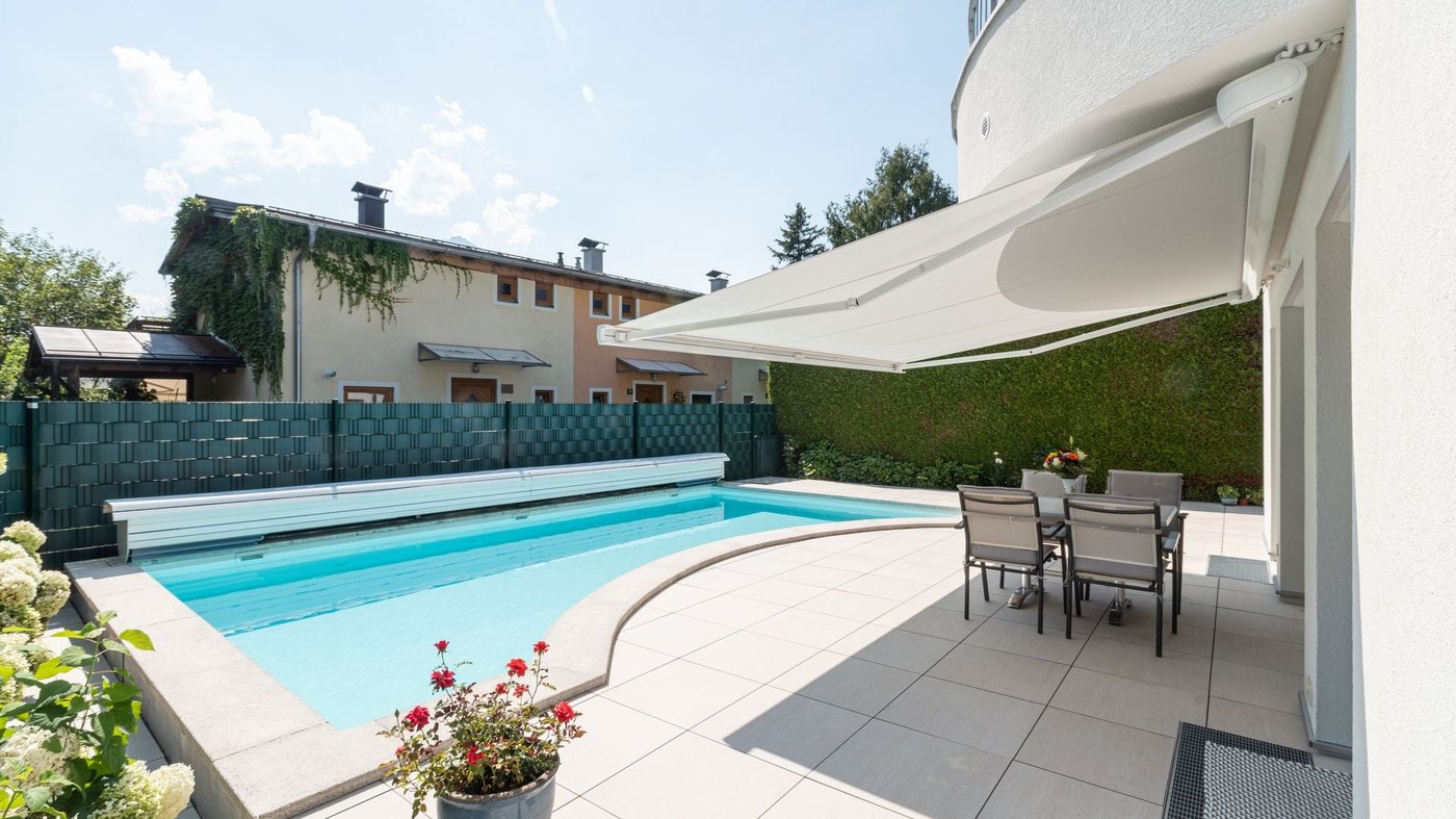 Hvid Markilux MX-3 kassettemarkise over en terrasse med pool i baggrunden